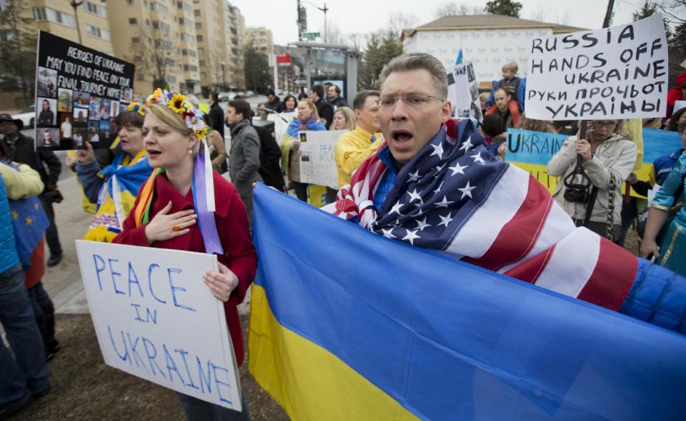 Moscow-born Dmitry Savransky, right, who holds dual citizenship, American and Russian, joins his Ukrainian wife Natalya Seay, left, during a protest rally in front of the Russian embassy, in Washington, Sunday, March 2, 2014. Igniting a tense standoff, Russian forces surrounded a Ukrainian army base Sunday just as the country began mobilizing in response to the surprise Russian takeover of Crimea. Outrage over Russia's tactics mounted in world capitals, with U.S. Secretary of State John Kerry calling on President Vladimir Putin to pull back from "an incredible act of aggression." (AP Photo/Manuel Balce Ceneta)