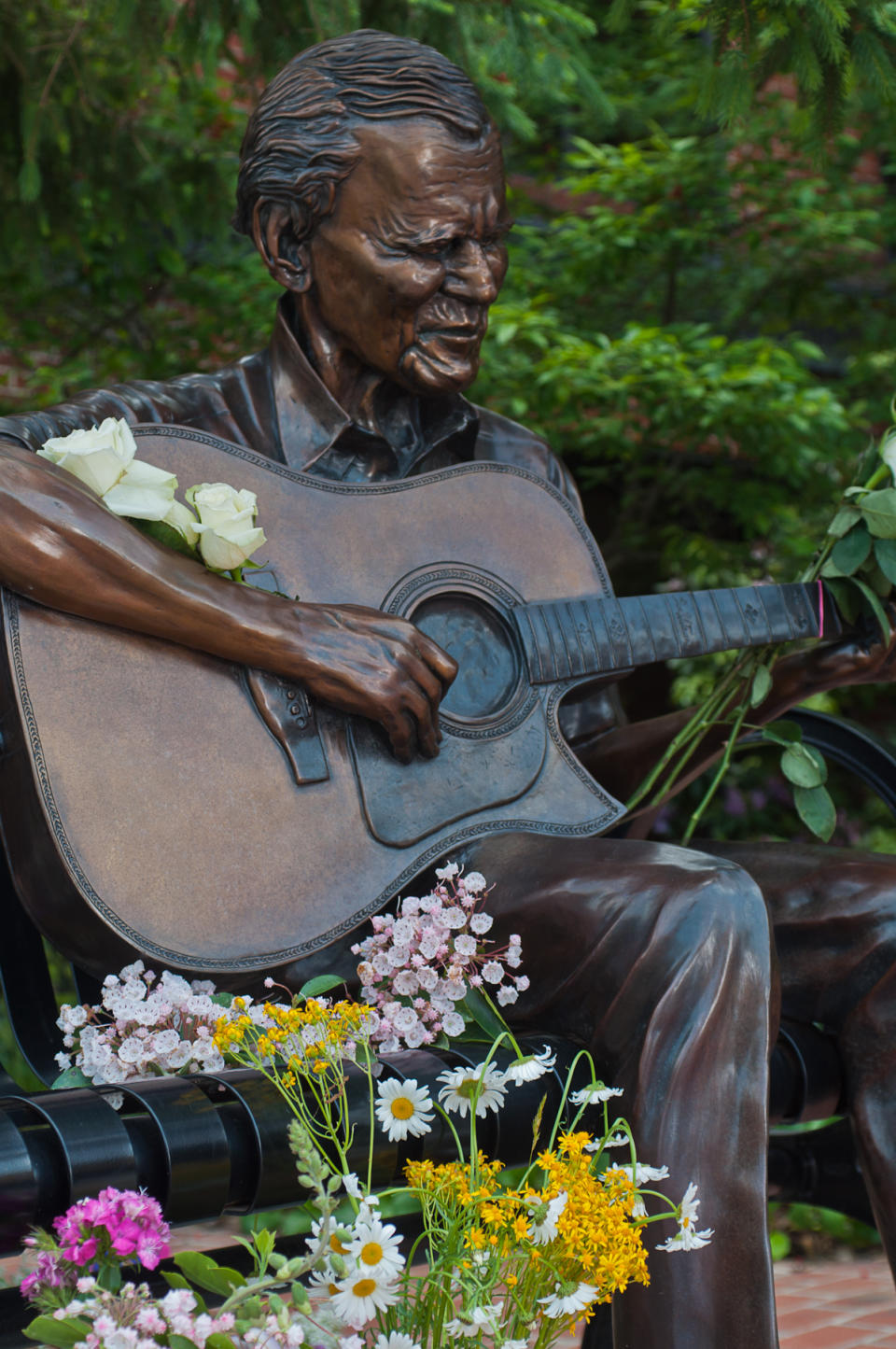 In this photo provided by Mast General Store, flowers adorn a statue of Arthel "Doc" Watson in downtown Boone, N.C., on Friday, May 25, 2012. The Grammy-winning folk musician Doc Watson is in critical condition but improving at a North Carolina hospital after colon surgery. (AP Photo/Mast General Store, Lynn Willis)