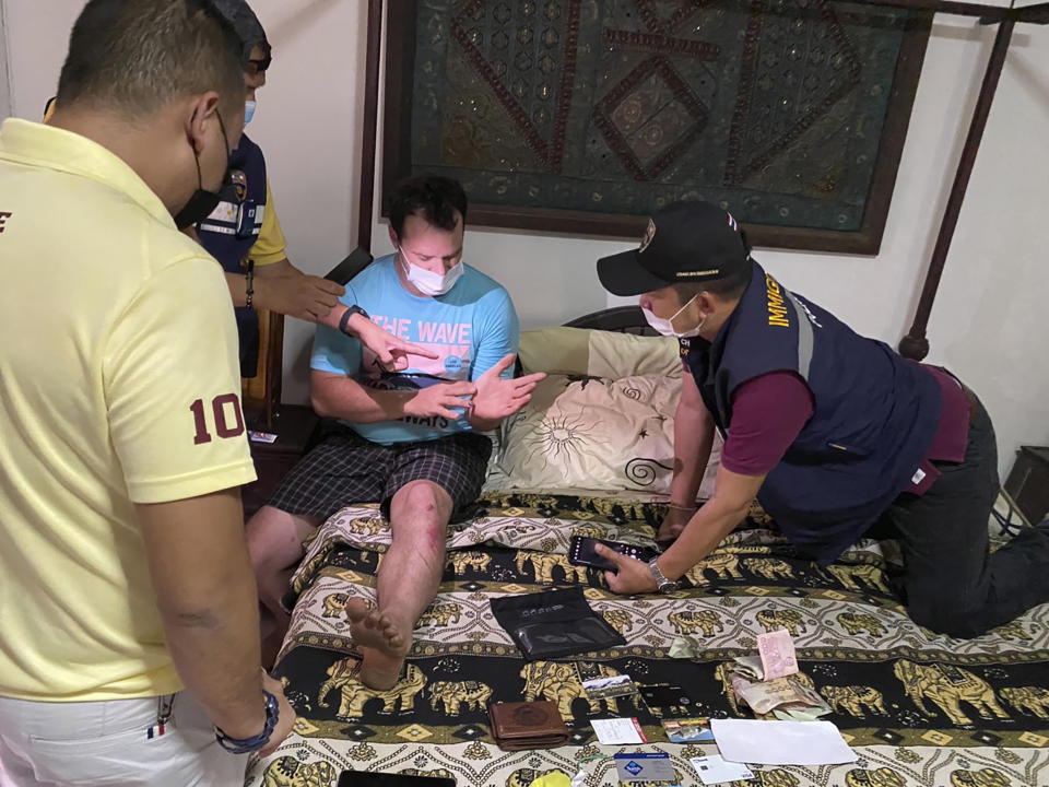 In this Thursday, May 6, 2021, photo released by the Thai Provincial Police Region 5, police arrest and interrogate American citizen Jason Matthew Balzer, center, in Chiang Mai province northern Thailand before charging him for intentionally murdering his pregnant wife in Nan province. (Thai Provincial Police Region 5 via AP)