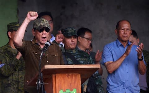 Philippines President Rodrigo Duterte raises a clenched fist, as he shouts declaring Marawi "liberated" during a ceremony inside the battle area of Bangolo district in Marawi on October 17, 2017 - Credit: AFP