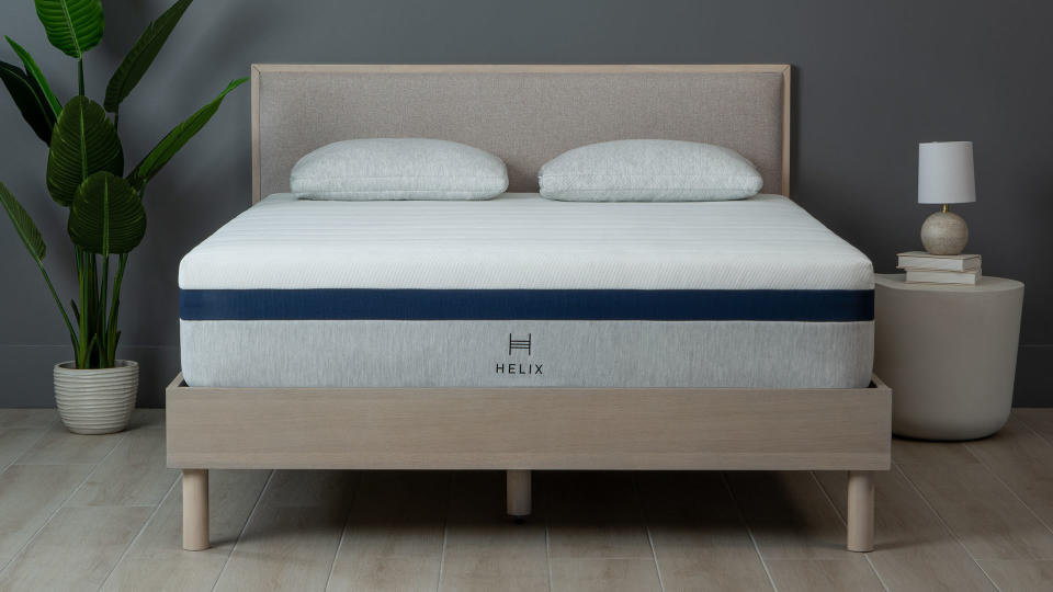 Helix Midnight mattress on a wooden bedframe, against a dark wall