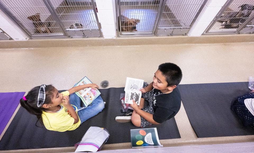 Lincoln Elementary students Mayte Aburto, left, and Ezikiel Franco read to dogs in the Visalia Animal Care Center on Tuesday, June 20, 2023. The 10 Exeter students in their group will have five visits with the dogs doing the summer.