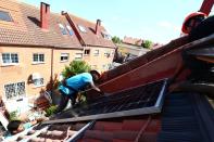 FILE PHOTO: Kauahou, Navarro and Pascual, workers of the installation company Alromar, set up solar panels on the roof of a home in Colmenar Viejo