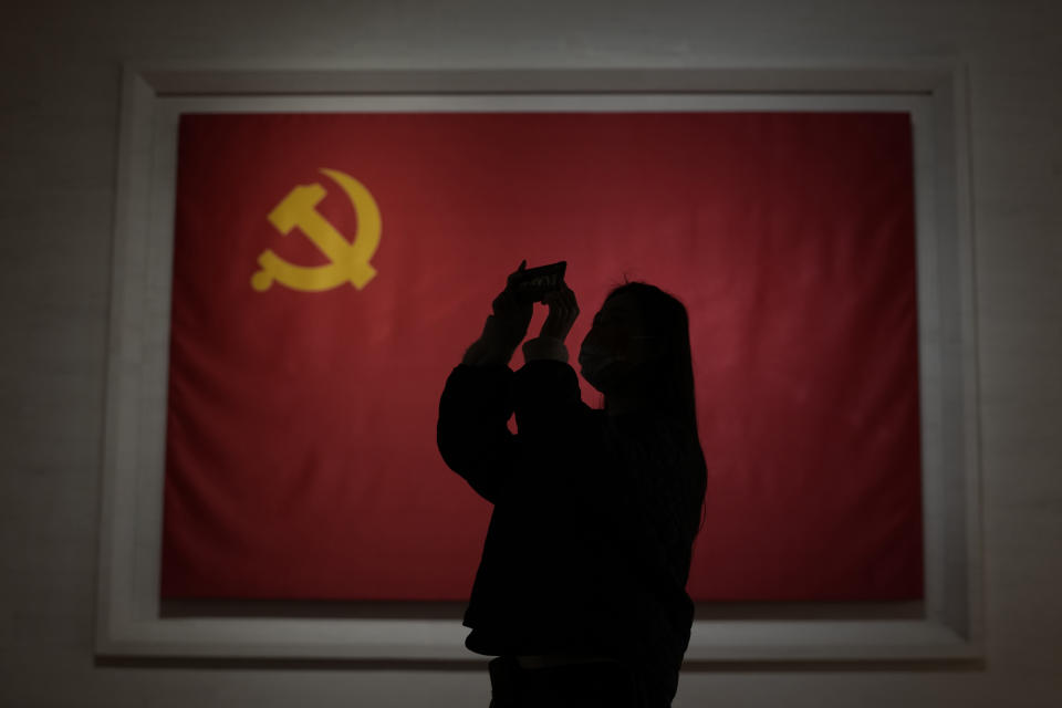 A visitor to the Museum of the Communist Party of China is silhouetted near the Chinese Communist Party flag in Beijing, China, Friday, Nov. 12, 2021. Chinese leader Xi Jinping emerges from a party conclave this week not only more firmly ensconced in power than ever, but also with a stronger ideological and theoretical grasp on the ruling Communist Party's past, present and future. (AP Photo/Ng Han Guan)