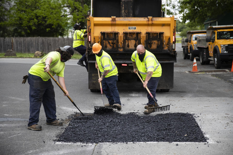 Employees of the Allentown, Pa., streets department patch a hole near Jordan Park in Allentown, Pa., Friday, May 29, 2020. Unfilled potholes, uncollected trash, un-mowed grass and, most significantly, fewer police on the street are some of what Allentown says it’s contemplating unless Washington helps it plug a multimillion-dollar budget hole left by the coronavirus pandemic. (AP Photo/Matt Rourke)