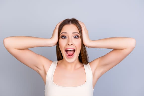 Woman with hands over ears screaming