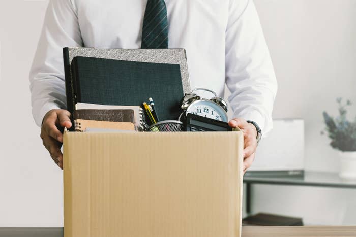 a person holding a box being let go from their job