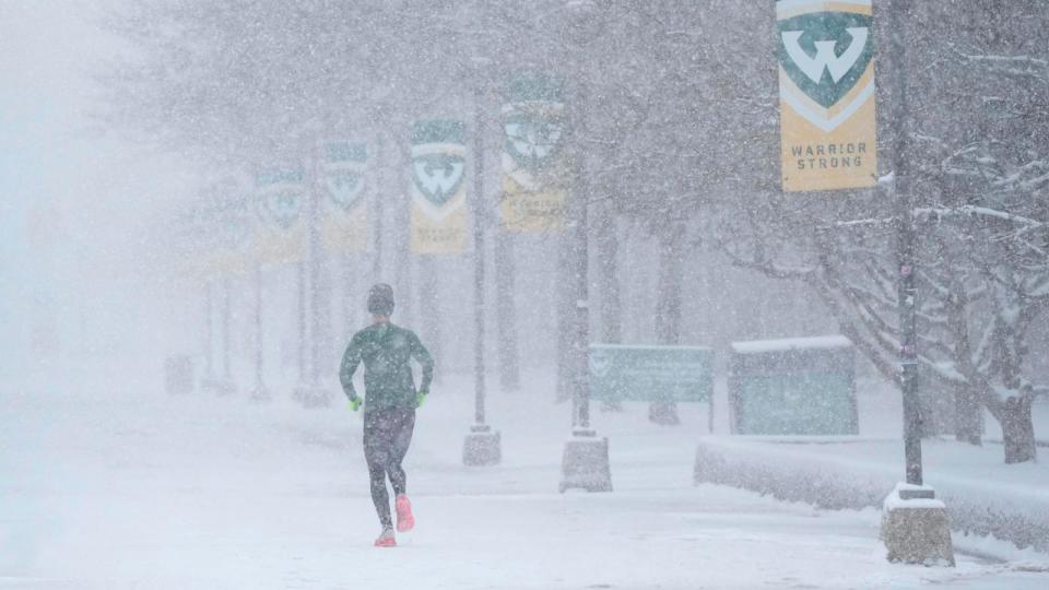 PHOTO: A jogger runs as snow falls on the campus of Wayne State University, March 22, 2024, in Detroit.  (Carlos Osorio/AP)