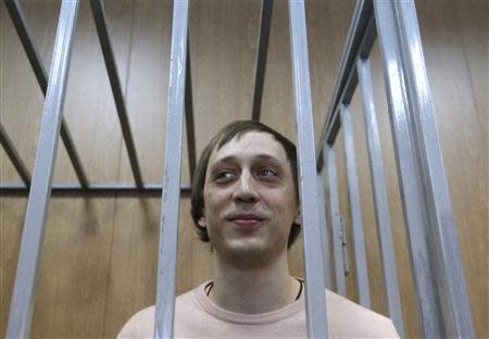 Former Bolshoi Theatre dancer Pavel Dmitrichenko stands inside the defendant's cage during a court hearing in Moscow December 3, 2013. REUTERS/Maxim Shemetov