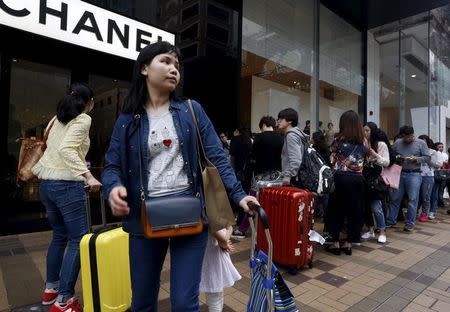 Mainland Chinese visitors wait outside a luxury store at a shopping district in Hong Kong March 19, 2015. REUTERS/Bobby Yip