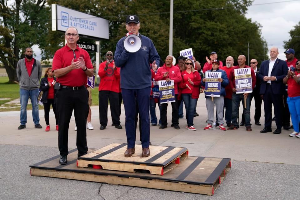 United Auto Workers president Shawn Fain, left, listens as President Joe Biden speaks to striking UAW members outside a General Motors facility on 26 September, 2023, in Van Buren Township, Michigan (Copyright 2023 The Associated Press. All rights reserved)