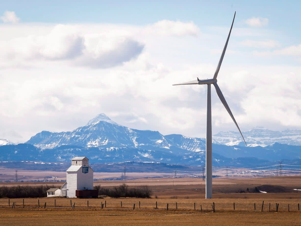 A wind turbine overshadows a grain elevator near Pincher Creek, Alta. Premier Danielle Smith says wind farms aren't a reliable source of electricity in Alberta. (Jeff McIntosh/Canadian Press - image credit)