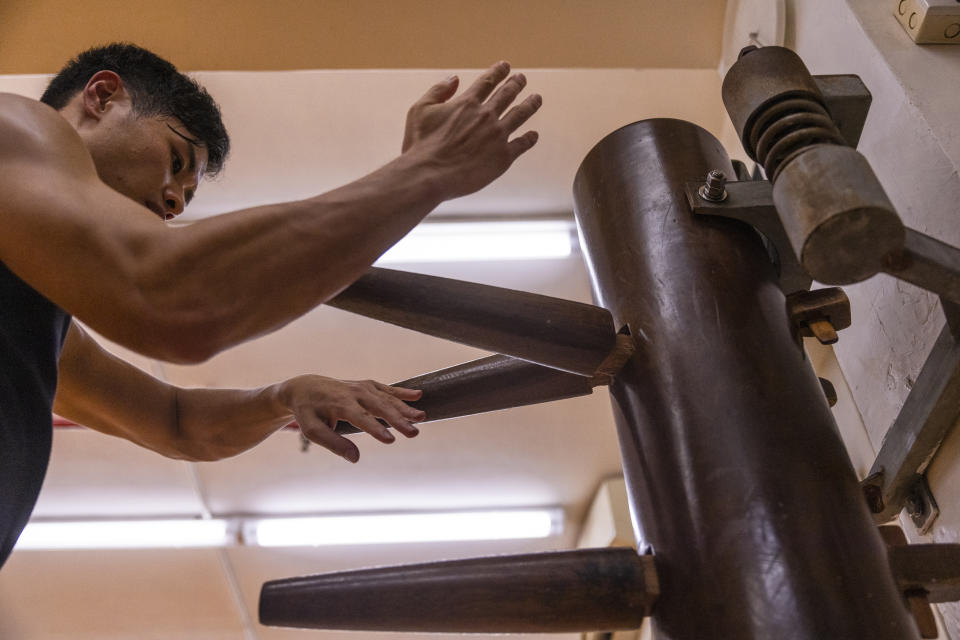 Adrian Li, 31, practices on a wooden dummy known as a 'Muk Yan Jong' during a Jeet Kune Do class in Hong Kong, Wednesday, July 19, 2023. (AP Photo/Louise Delmotte)