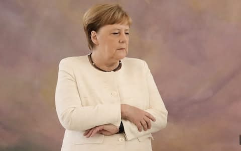 Mrs Merkel held her arms during a shaking episode in Berlin last month - Credit: OUTKAY NIETFELD/AFP/Getty Images