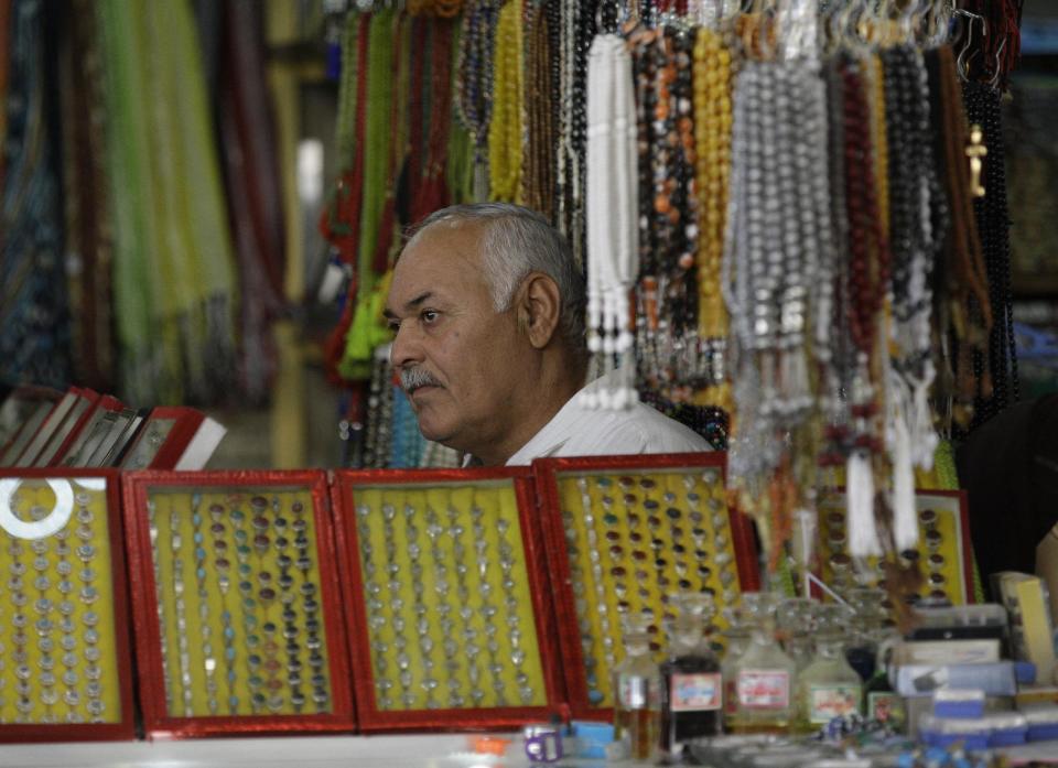 In this photo taken in Tuesday, Oct. 30, 2012, shop owner, Yousif Jassim Mohammed sits as he waits for customers in Najaf, Iraq. The plunge in Iran's currency is proving bad for business in neighboring Iraq. Fewer Iranians are now able to afford visits to Shiite holy sites here and elsewhere in Iraq because each dollar or Iraqi dinar now costs roughly three times what it did as recently as last year. That has pushed the price of organized tours up sharply and made Iraqi merchants far less willing to accept rials as payment. (AP Photo/Khalid Mohammed)