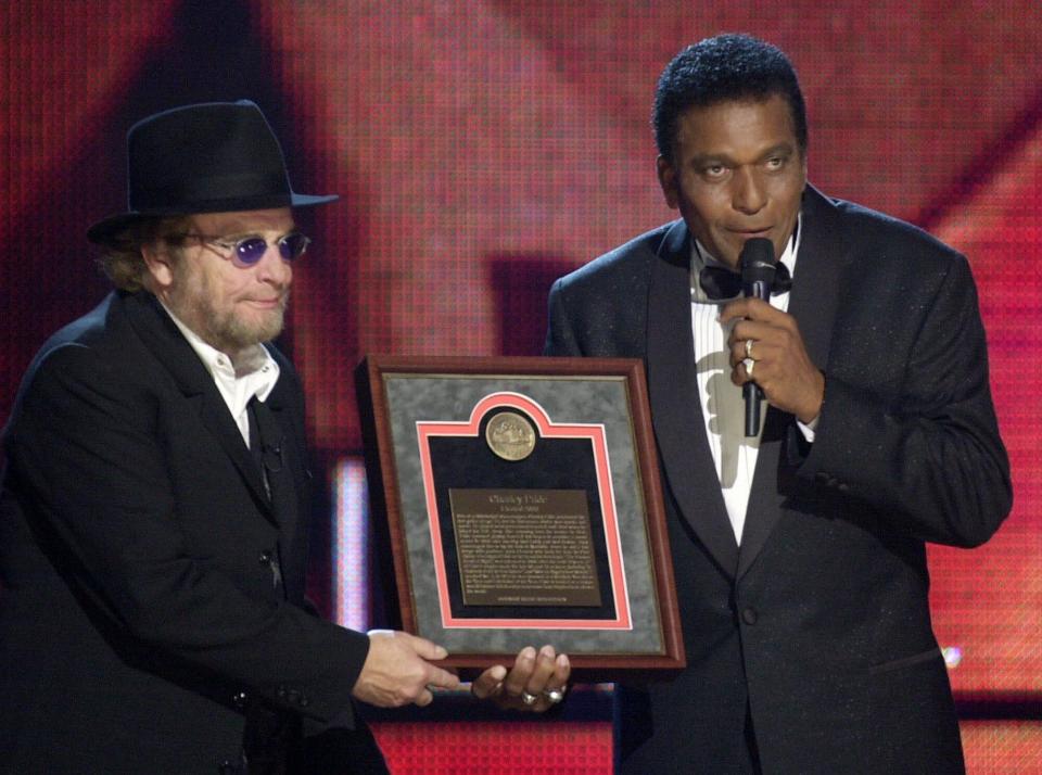 CORRECTS FIRST NAME TO CHARLEY, INSTEAD OF CHARLIE FILE - In this Oct. 4, 2000, file photo, Charley Pride, right, receives his Country Music Hall of Fame plaque from Merle Haggard at the Country Music Association Awards show at the Grand Ole Opry House in Nashville, Tenn. Pride, the son of sharecroppers in Mississippi and became one of country music’s biggest stars and the first Black member of the Country Music Hall of Fame, has died at age 86. Pride died Saturday, Dec. 12, 2020, in Dallas of complications from Covid-19, according to Jeremy Westby of the public relations firm 2911 Media. (AP Photo/Charlie Neibergall, File)