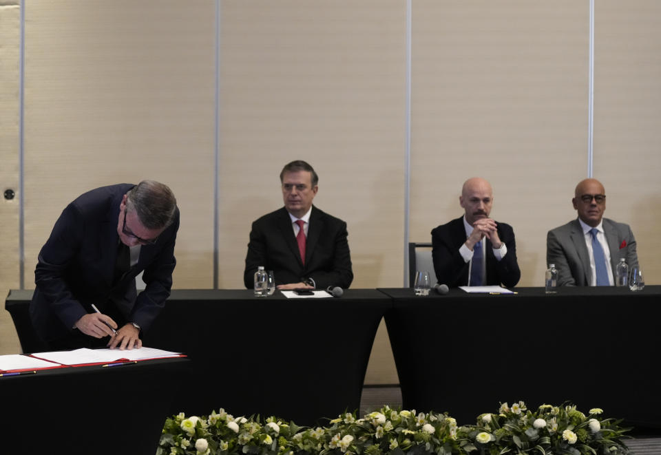 Venezuelan opposition delegate Gerardo Blyde Perez, left, signs an agreement to create a U.N.-managed fund to finance health, food and education programs for the poor during a ceremony at a hotel in Mexico City, Saturday, Nov. 26, 2022. The agreement signed by representatives of Venezuelan President Nicolás Maduro and the opposition marked the resumption of long-stalled negotiations meant to find a common path out of their country's complex crisis. The U.S. government, in response, agreed to allow oil giant Chevron to pump Venezuelan oil. (AP Photo/Fernando Llano)