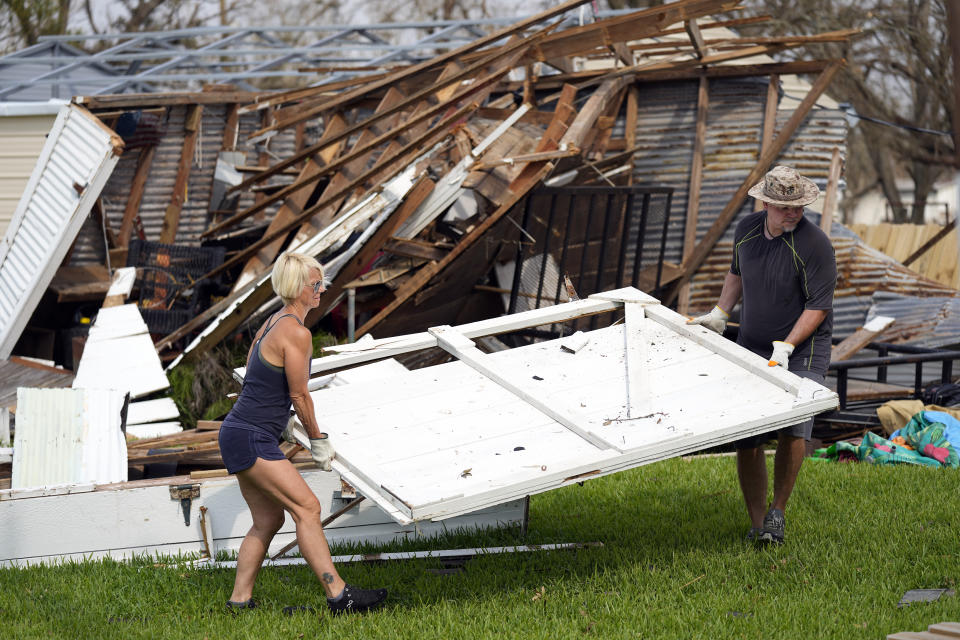 Scott and Carol Blazer carry a door from their destroyed barn, in the aftermath of Hurricane Ida, Thursday, Sept. 2, 2021, in Golden Meadow, La. (AP Photo/David J. Phillip)