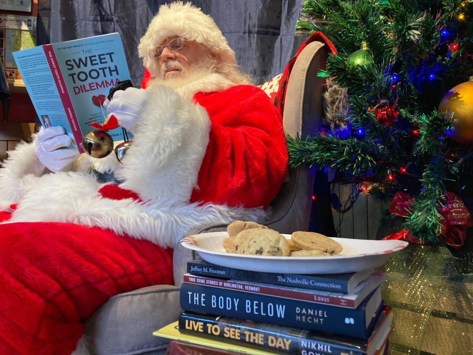 Santa Claus is dismayed to read of the dangers of sugar as he reads "The Sweet Tooth Dilemma" by Vermont author Andrea Grayson as a plate of cookies sits atop a pile of Vermont-related books in the entryway of the Homeport store Nov. 24, 2023 on the Church Street Marketplace in Burlington.