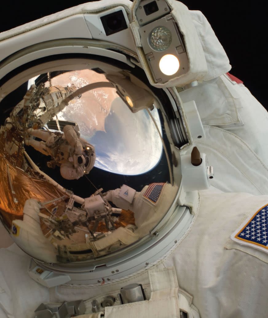 A close-up of Astronaut John Grunsfeld shows the reflection of Astronaut Andrew Feustel, perched on the robotic arm and taking the photo. The pair teamed together on three of the five spacewalks during Servicing Mission 4 in May 2009. 
