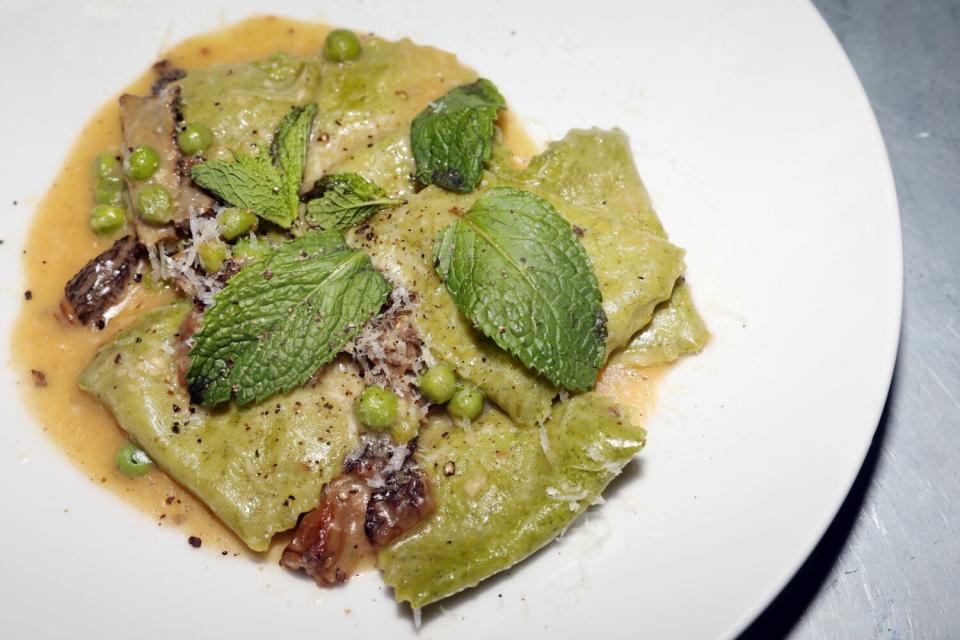 Green mezzelune pasta in a bowl.