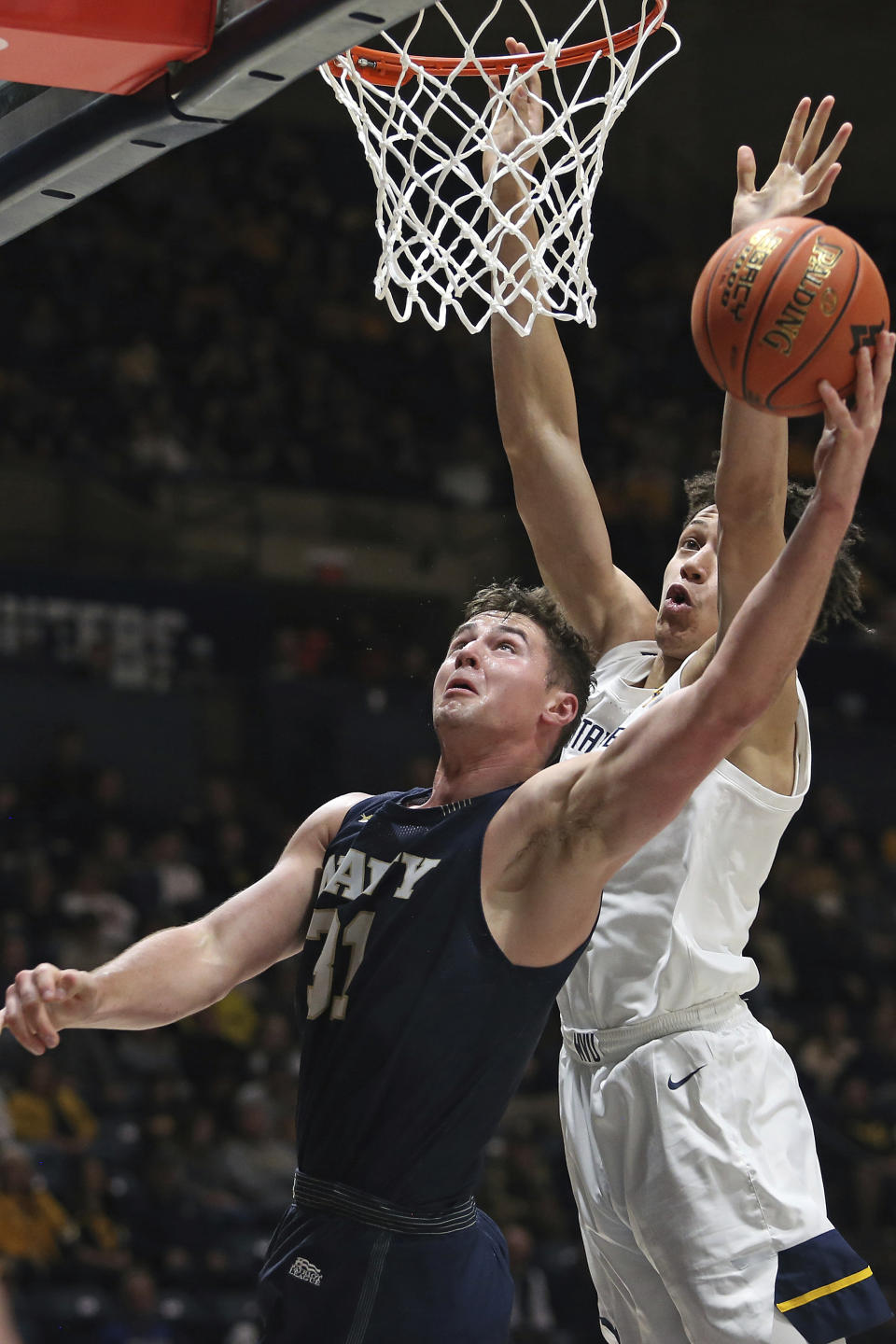 Navy forward Daniel Deaver (31) is defended by West Virginia forward James Okonkwo during the first half of an NCAA college basketball game in Morgantown, W.Va., Wednesday, Dec. 7, 2022. (AP Photo/Kathleen Batten)
