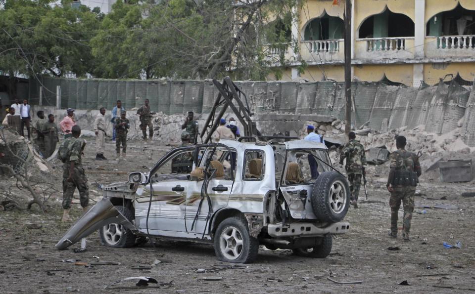Somali soldiers stand near the wreckage of a car bomb attack that targeted a checkpoint in Mogadishu, Somalia Tuesday, March 21, 2017. The car bomb exploded Tuesday at a military checkpoint near Somalia's presidential palace in the capital, after soldiers tried to stop the car and the bomber tried to speed through the checkpoint, killing a number of people, police said. (AP Photo/Farah Abdi Warsameh)