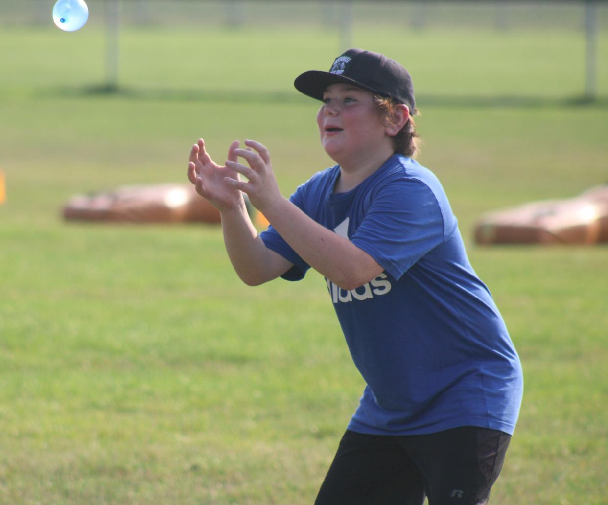 A camper looks to make a catch with a water balloon during a drill conducted at the Cheboygan youth football camp on Monday.