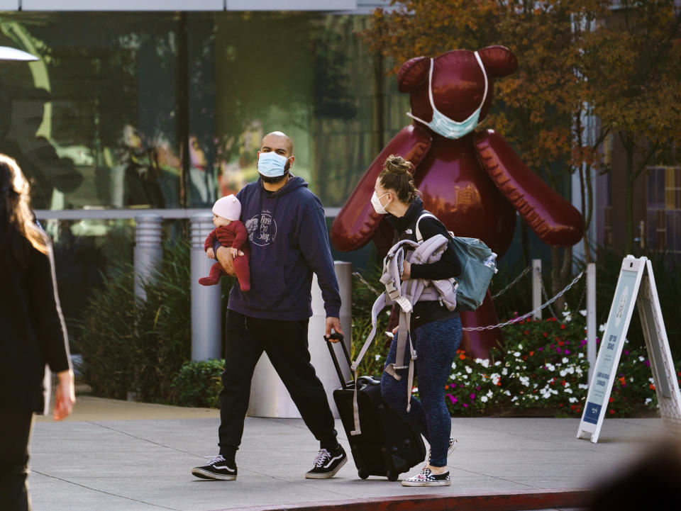 A family wears protective face masks as they leave the Los Angeles Children's Hospital in Los Angeles, Tuesday, Jan. 5, 2021. Los Angeles is the epicenter of California's surge that is expected to get worse in coming weeks when another spike is expected after people traveled or gathered for Christmas and New Year's. Much of the state is under a stay-home order and open businesses are operating with limited capacity. (AP Photo/Damian Dovarganes)