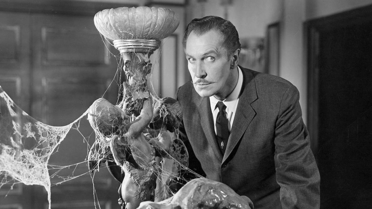 vincent price stands spooked next to a cobwebfilled lamp in a scene from house on haunted hill, a good housekeeping pick for best halloween movies