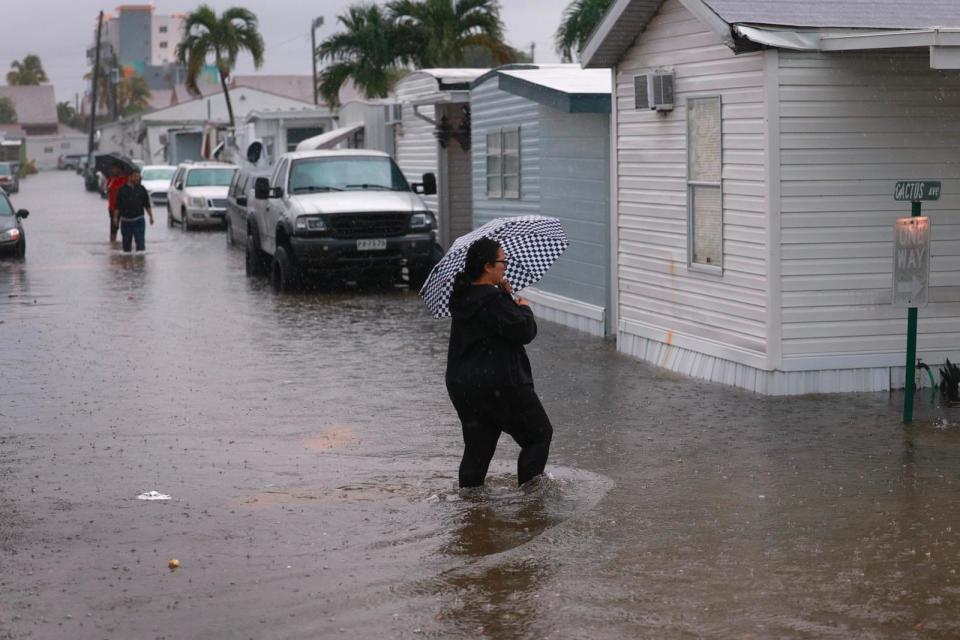 PHOTO: People walk through a flooded street in Hallandale Beach, FL, June 12, 2024,  (Joe Raedle/Getty Images)