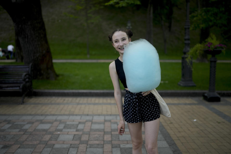 A girl holds cotton candy at a square in Kyiv, Ukraine, Friday, June 10, 2022. With war raging on fronts to the east and south, the summer of 2022 is proving bitter for the Ukrainian capital, Kyiv. The sun shines but sadness and grim determination reign. (AP Photo/Natacha Pisarenko)