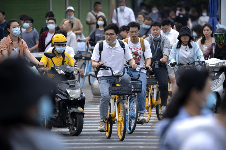 People ride bicycles across an intersection during rush hour in Beijing, Friday, July 2, 2021. A small but visible handful of urban Chinese are rattling the ruling Communist Party by choosing to "lie flat," or reject high-status careers, long work hours and expensive cities for a "low-desire life." That clashes with party ambitions to make China a wealthier consumer society. (AP Photo/Mark Schiefelbein)