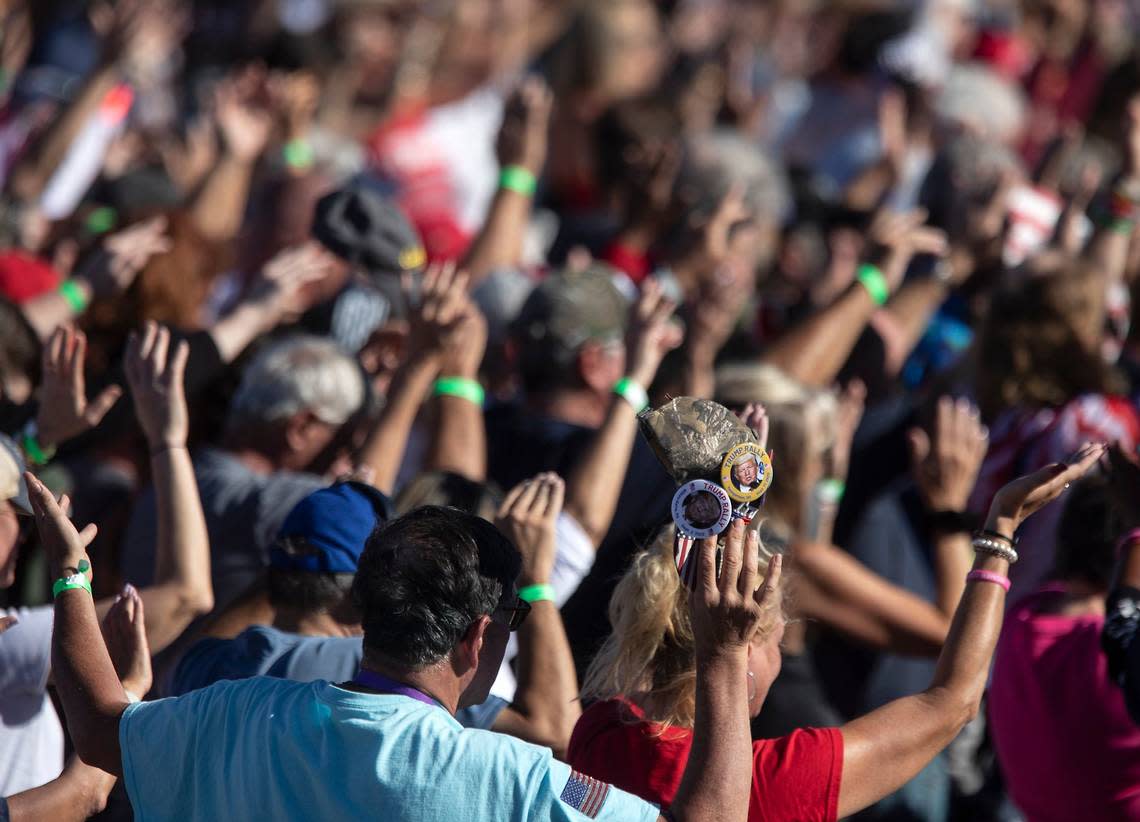 People lift their hands in prayer at the start of a rally featuring former president Donald Trump at Wilmington International Airport on Friday, Sept. 23, 2022.