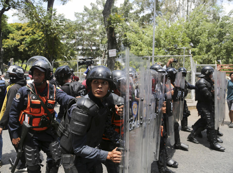 A cordon of Venezuelan National Police officers retreat when confronted by demonstrators who were temporarily blocked by police from getting to a rally against the government of President Nicolas Maduro in Caracas, Venezuela, Saturday, March 9, 2019.(AP Photo/Fernando Llano)