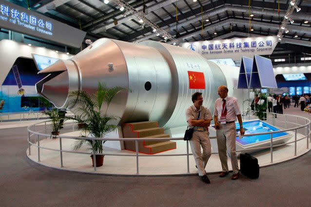 Visitors stand next to a model of the space station at the 8th China International Aviation and Aerospace Exhibition in Zhuhai. Source: AAP