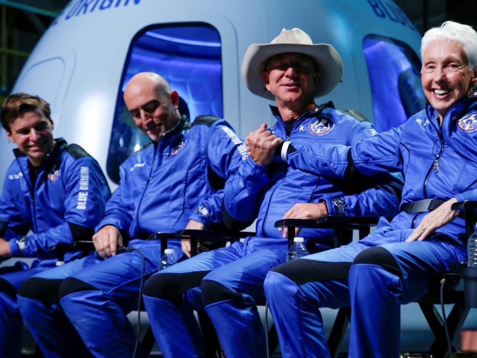 jeff bezos and wally funk shaking hands onstage in flightsuits