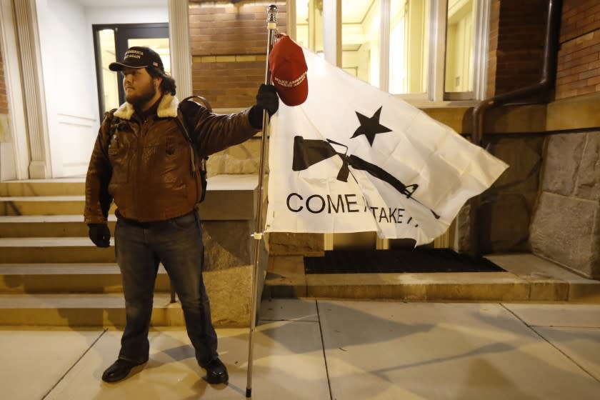 Kem Regik, of Virginia, stands on the sidewalk before a pro gun rally, Monday, Jan. 20, 2020, in Richmond, Va. There was a light crowd early morning Monday outside the Capitol ahead of the rally. (AP Photo/Julio Cortez)