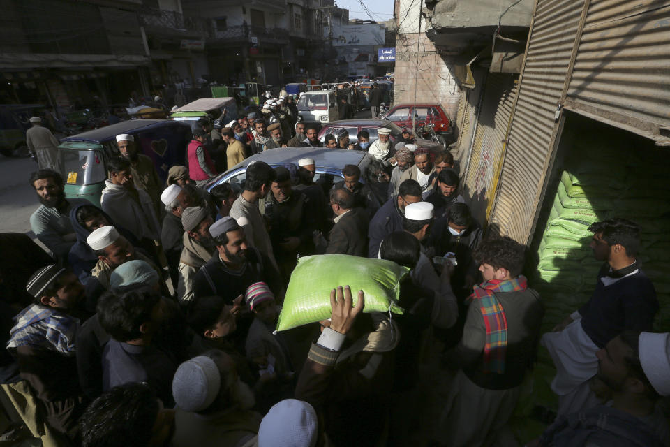 People wait in long queue to buy sack of wheat-flour on subsidize rate at a sale point, in Peshawar, Pakistan, Tuesday, Feb. 14, 2023. Cash-strapped Pakistan nearly doubled natural gas taxes Tuesday in an effort to comply with a long-stalled financial bailout, raising concerns about the hardship that could be passed on to consumers in the impoverished south Asian country. Pakistan's move came as the country struggles with instability stemming from an economic crisis. (AP Photo/Muhammad Sajjad)