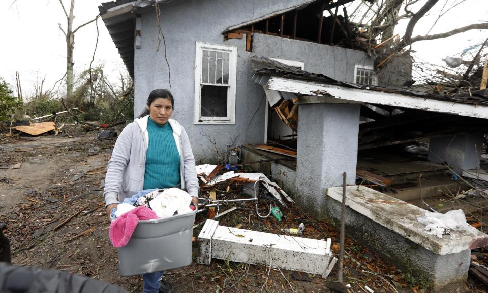 Margarita Morales, carries her possessions out of a house she shared with two other people after a tornado destroyed the residence, Saturday, Jan. 21, 2017 in Hattiesburg, Miss. The tornado was part of a wall of stormy weather traveling across the region, bringing with it rain and unstable conditions. (AP Photo/Rogelio V. Solis)