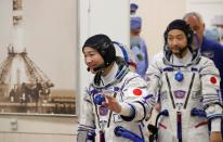 Japanese entrepreneur Yusaku Maezawa and his production assistant Yozo Hirano walk after donning space suits shortly before their launch to the International Space Station (ISS) at the Baikonur Cosmodrome