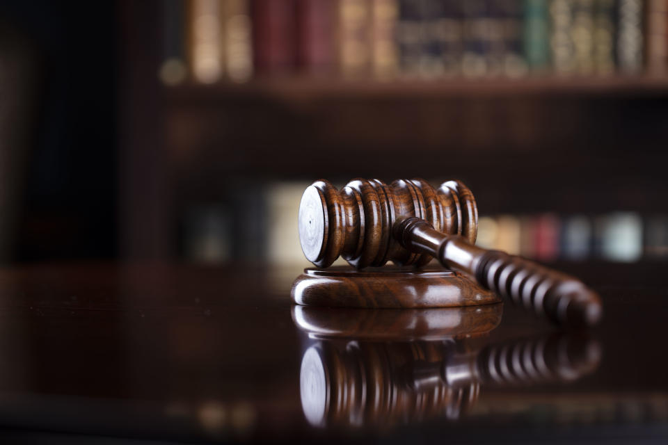 Judge‘s gavel on brown shining table and bookshelf background.