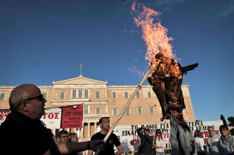 Protesters burn an effigy of a greek worker in front of the parliament in Athens on April 28, 2013. The Greek parliament voted to adopt a law that provides for the dismissal of 15,000 civil servants as part of austerity measures imposed by the country's international creditors