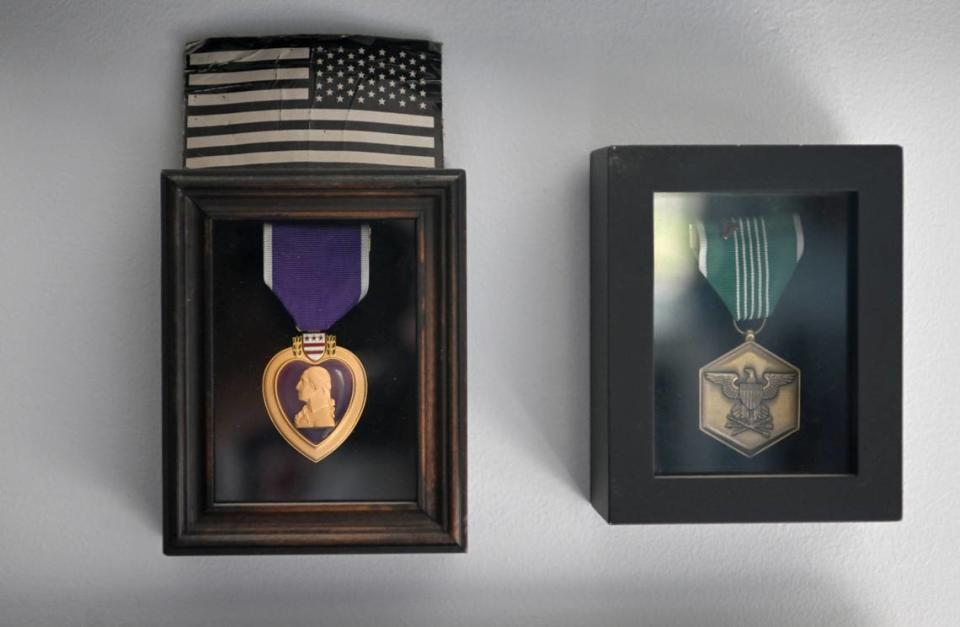 A Purple Heart and Commendation Medal are framed and hang on the wall in Adam Hartswick’s home.