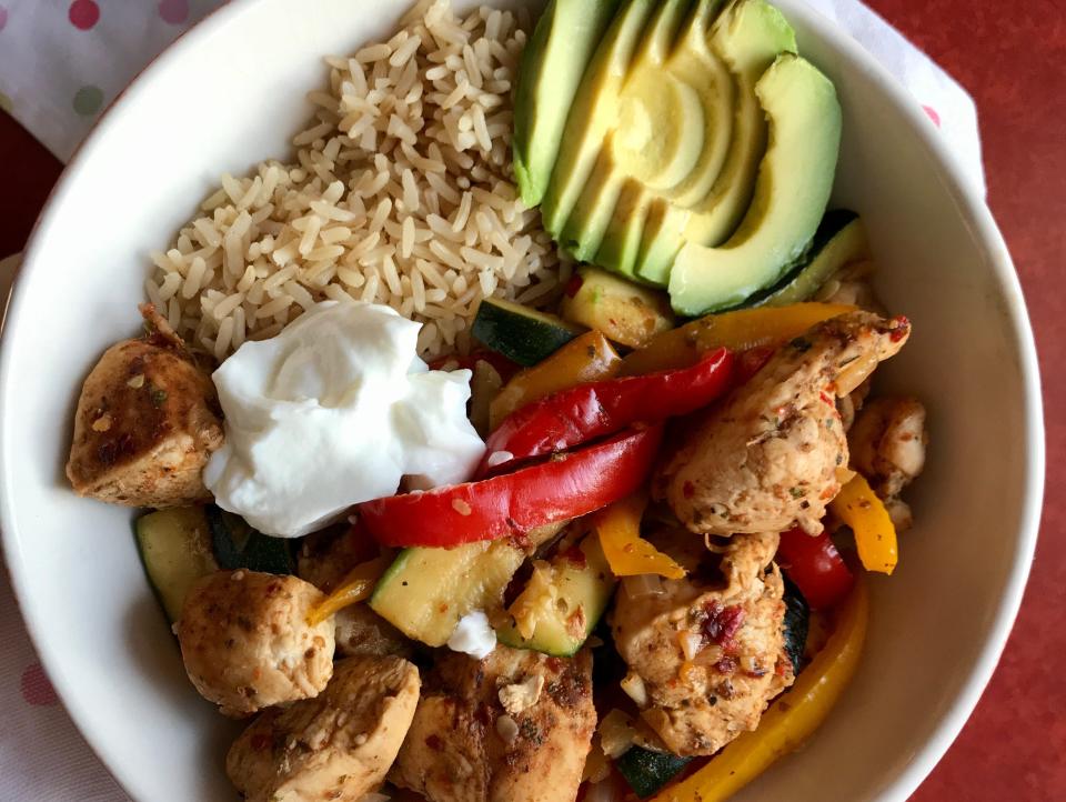 A bowl of rice, chicken, peppers, avocado, and Greek yogurt.