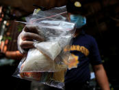<p>A member of the Philippine National Police (PNP) investigation unit shows confiscated methamphetamine, known locally as Shabu, along with Philippines pesos seized from suspected drug pushers during an operation by the police in Quiapo city, metro Manila, Philippines on July 3, 2016. (REUTERS/Romeo Ranoco) </p>