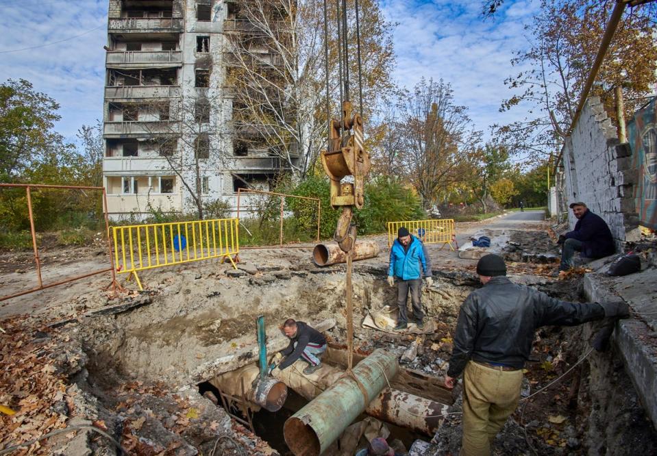 Ukrainian workers repair damaged heating communications of damaged residential buildings in Kharviv (EPA)