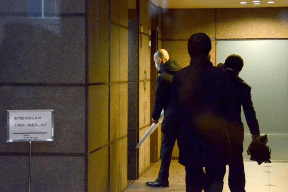 Tokyo prosecutors enter a building where the office of Junichiro Hironaka, a Japanese lawyer of former Nissan Chairman Carlos Ghosn, is located, in Tokyo Wednesday, Jan. 8, 2020. Prosecutors raided Hironaka's office where Ghosn had visited regularly before skipping bail last week and fleeing to Lebanon. Ghosn was under strict bail conditions while preparing for his trial on financial misconduct allegations. But he had been allowed to use a computer at his lawyer's office under those conditions. (Kyodo News via AP)