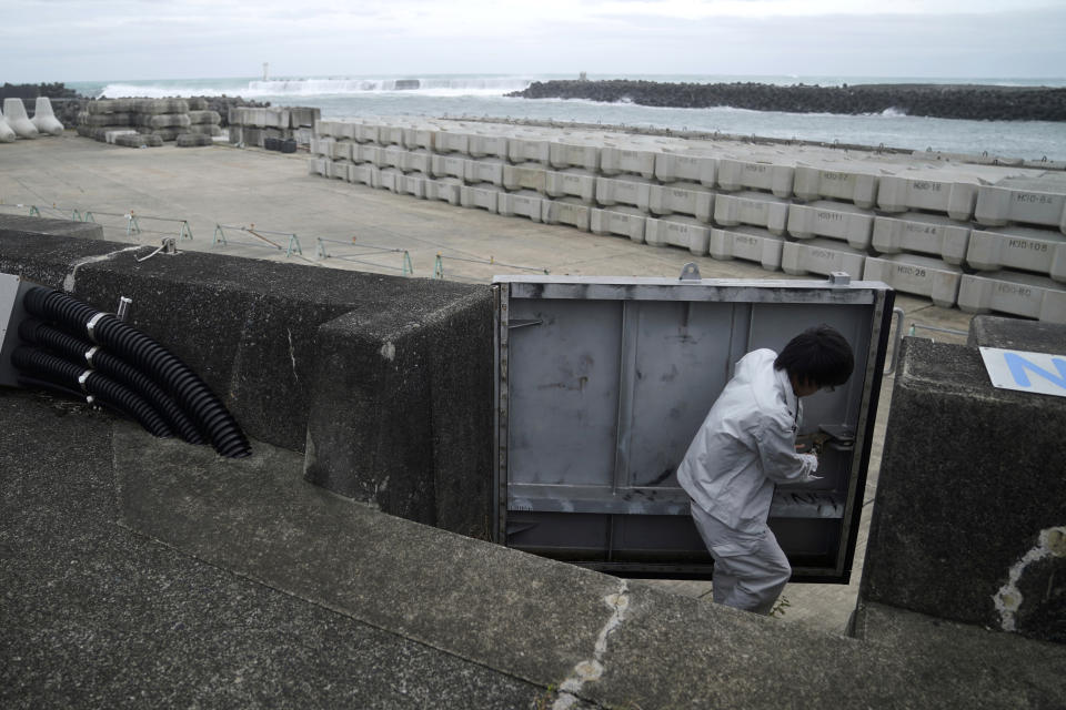 A Kiho town official closes a door of a coastal levee as Typhoon Hagibis approaches at a port in town of Kiho, Mie Prefecture, Japan Friday, Oct. 11, 2019. A powerful typhoon is advancing toward the Tokyo area, where torrential rains are expected this weekend. (AP Photo/Toru Hanai)