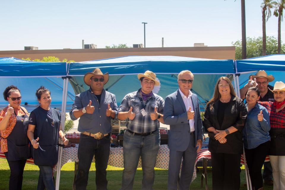 Outgoing Desert Sands superintendent Scott Bailey (blue suit) and incoming superintendent Kelly May-Vollmar (black suit) pose with Desert Sands nutrition services staff during a farmers market event for kids in La Quinta, Calif., on June 30, 2022.